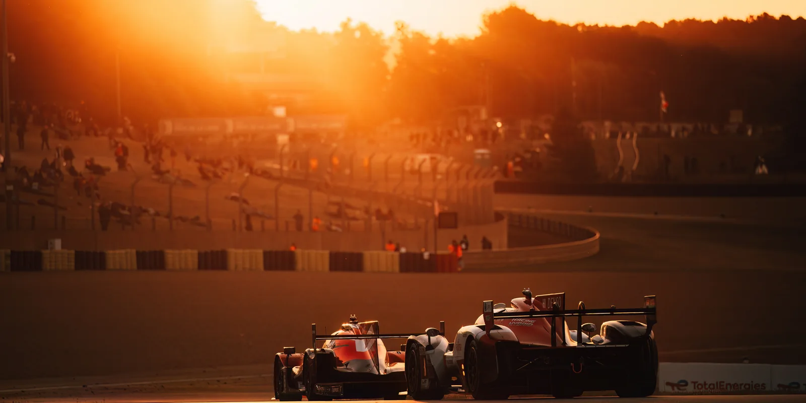 Race cars on track at sunset